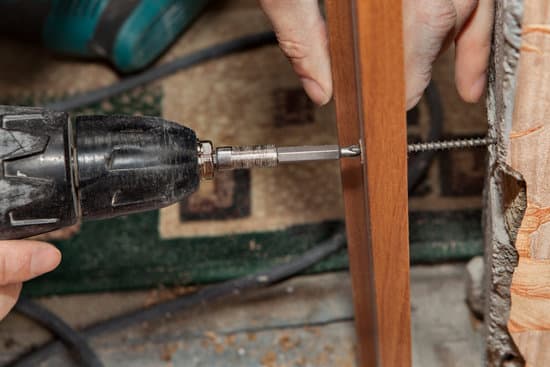 Close-up, use the screwdriver cordless drill for hanging interior door, screwing a screw for fixing the jamb to the wall.