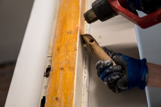 Detail of removing old white paint from door frame with heat gun and scraper